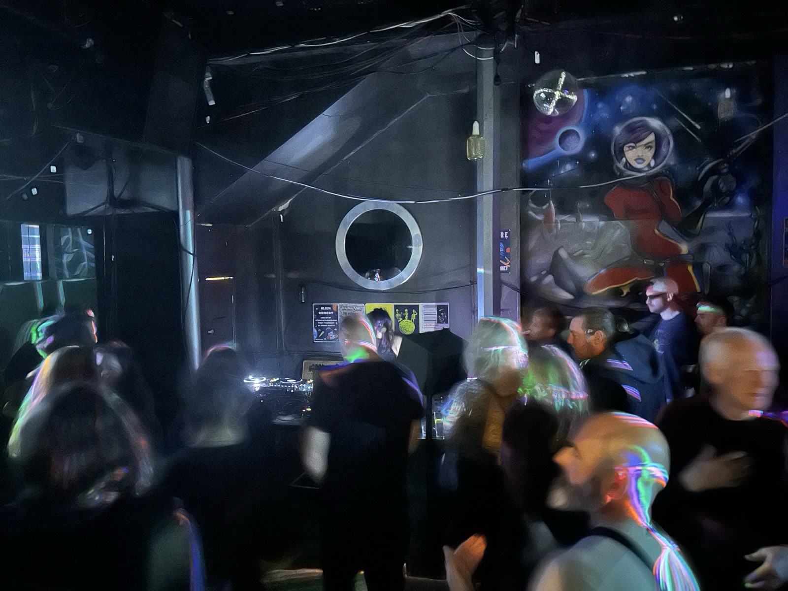 A crowded dance floor at a Cable Management night under a mural